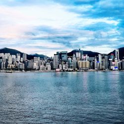 City at waterfront against cloudy sky