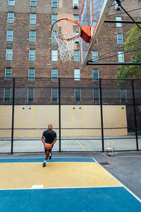 Man playing basketball by building in city