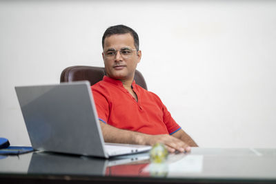 Portrait of mid adult man using mobile phone while sitting on table