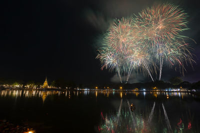 Firework display over lake at night