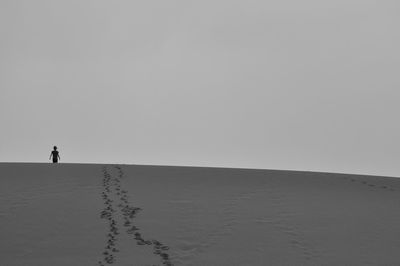 Silhouette person walking on landscape against clear sky