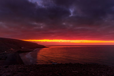Scenic view of sea against dramatic sky during sunset