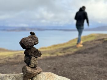 Rear view of man standing on rock against sky