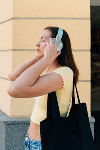 Portrait of young woman standing against wall