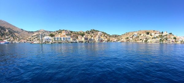 Scenic view of sea by town against clear blue sky