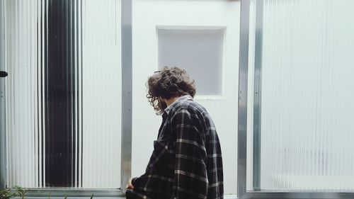 Side view of young man looking through window