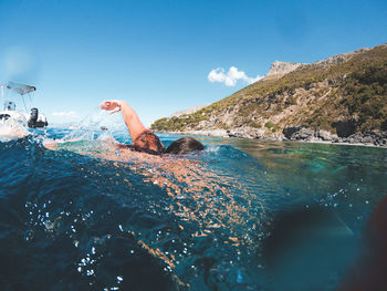 Man swimming in sea against sky