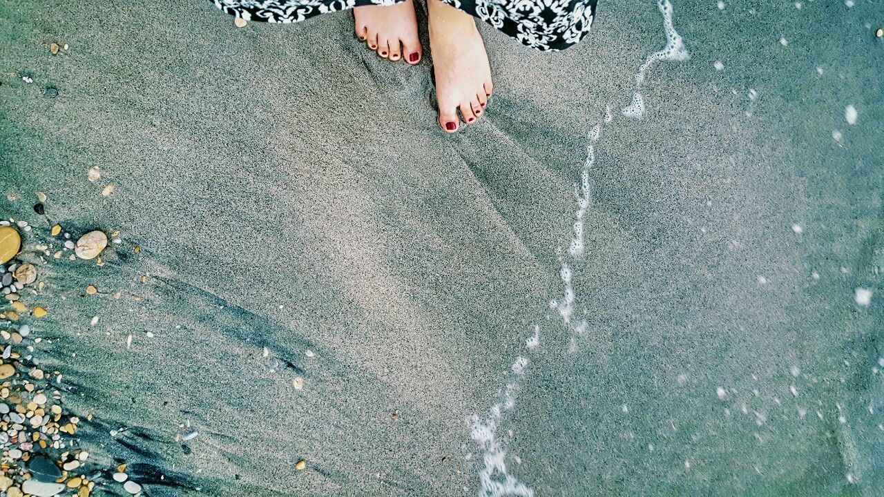 LOW SECTION OF WOMAN STANDING ON SHORE