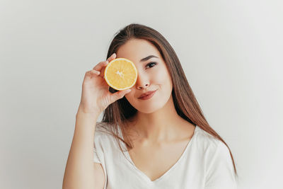 Portrait of a woman holding apple against white background