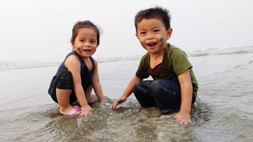Portrait of happy siblings at beach