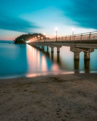 Bridge over river against sky in city at night