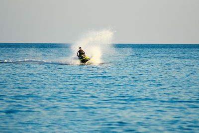 Man riding horse in sea against clear sky