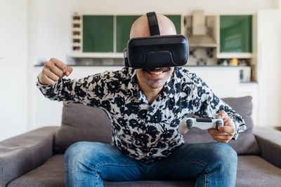 Midsection of man using mobile phone while sitting on sofa