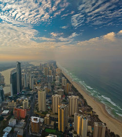 High angle view of modern buildings by sea against cloudy sky