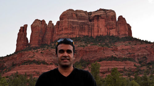 Portrait of man standing against rock formation