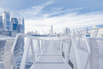 White pier on lake in city against sky