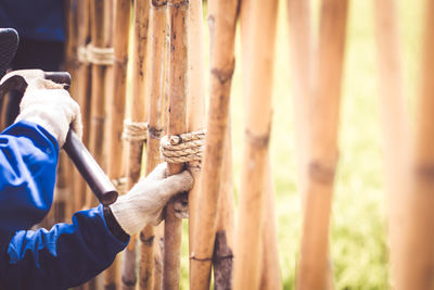 Midsection of man repairing wooden fence