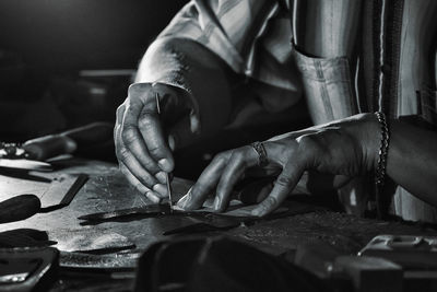 Midsection of man cutting leather at table in workshop