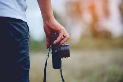 Midsection of man holding camera