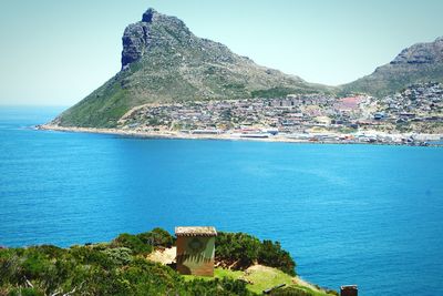 Scenic view of sea by town against clear blue sky