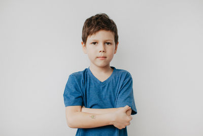 A preschool boy in a blue t-shirt on a light background shows looking at the camera. high quality