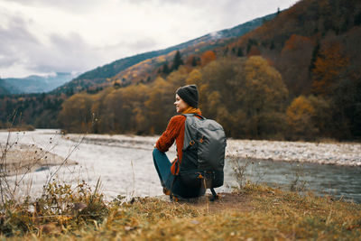 Rear view of woman sitting on mountain against sky