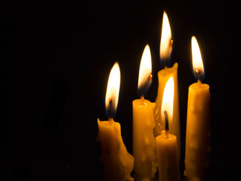 Close-up of lit candles in darkroom