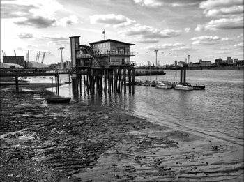 Boats in harbor against cloudy sky