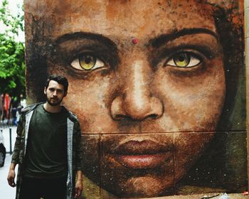 Portrait of young man standing against wall