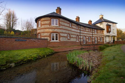 View of old building by canal against sky