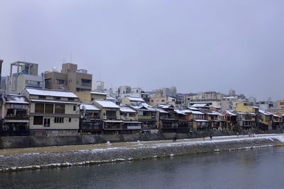 Cityscape by river against clear sky