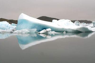 Ice floating on water in sea against sky