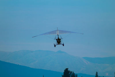 Low angle view of helicopter flying against blue sky