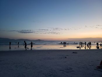 Silhouette people on beach against sky during sunset