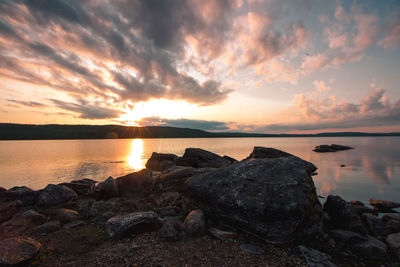 Rocks on shore against sky during sunset