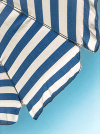 Low section of person standing on umbrella against clear blue sky