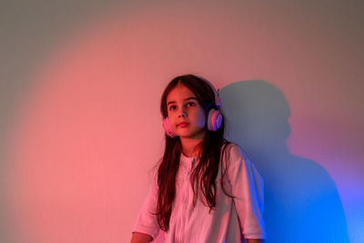 Beautiful girl in headphones listening to music in neon light