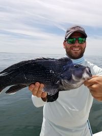 Portrait of man holding fish against sea