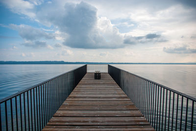 Pier on sea against cloudy sky