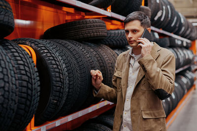 Man talking on phone while choosing tire at store