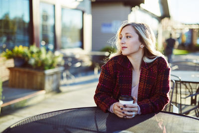 Young woman sitting at sidewalk cafe