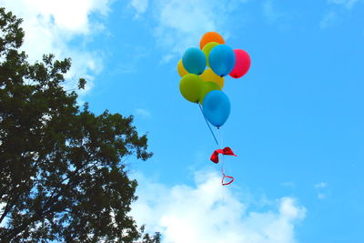 Low angle view of balloons flying against blue sky