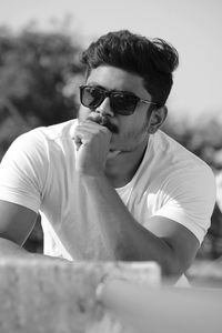 Portrait of young man wearing sunglasses sitting outdoors