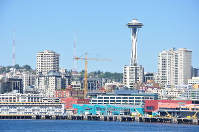 Space needle in city by sea against clear sky