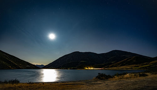 Scenic view of lake and mountains against sky at night
