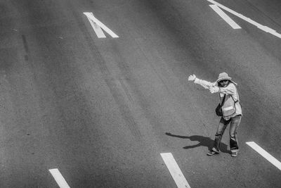 High angle view of man gesturing while standing on road