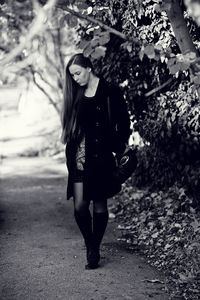 Full length of young woman standing against tree