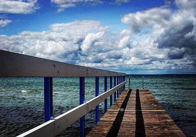 Pier on sea against cloudy sky