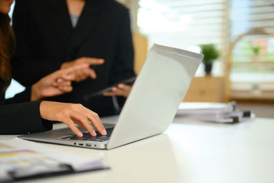 Midsection of businessman using laptop on table