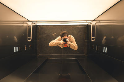 Directly above shot of man photographing with digital camera in elevator